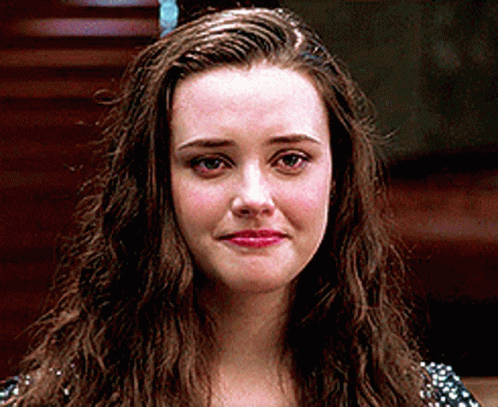 a woman with long brown hair is looking at the camera with a sad look on her face .