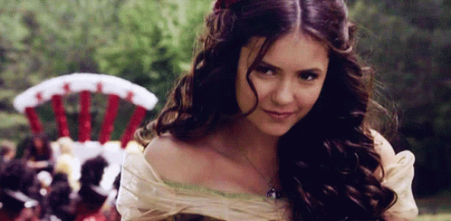 A Woman With Long Brown Hair Is Smiling And Looking At The Camera GIF