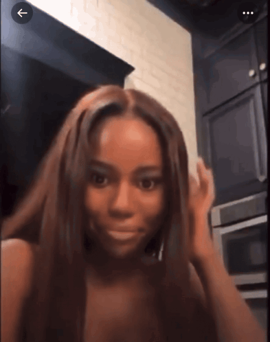a woman with long brown hair is standing in a kitchen with an arrow pointing to the right