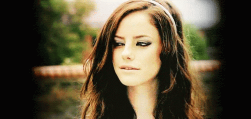 A Woman With Long Brown Hair Wearing A Headband Looks At The Camera GIF