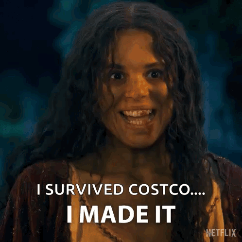 A Woman With Long Curly Hair Is Smiling And Saying `` I Survived Costco ... I Made It '' . GIF