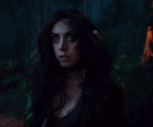 A Woman With Long Dark Hair And Feathers In Her Hair GIF