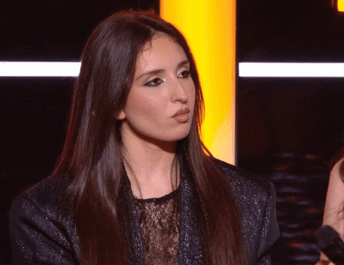 A Woman With Long Dark Hair Is Looking At The Camera GIF