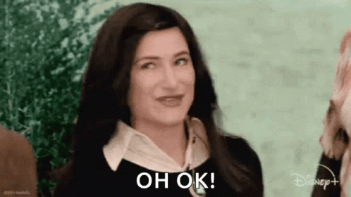 A Woman With Long Dark Hair Is Smiling And Says `` Oh Ok '' . GIF
