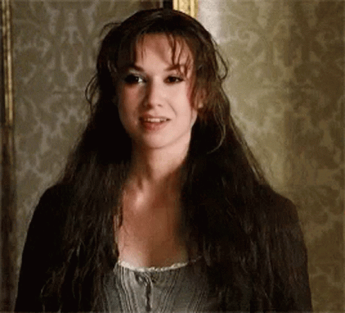 A Woman With Long Dark Hair Is Standing In Front Of A Wall . GIF