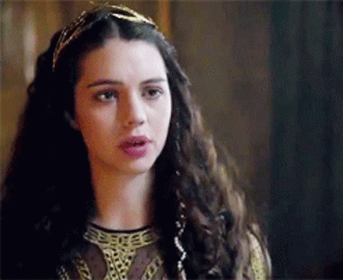 A Woman With Long Dark Hair Is Wearing A Headband And A Crown . GIF