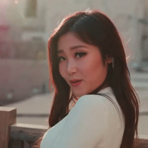 A Woman With Long Dark Hair Is Wearing A White Shirt GIF