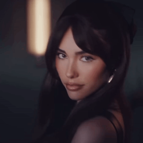 A Woman With Long Dark Hair Looks At The Camera GIF