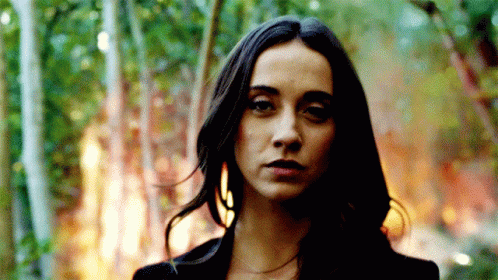 A Woman With Long Dark Hair Stands In Front Of A Forest Fire GIF