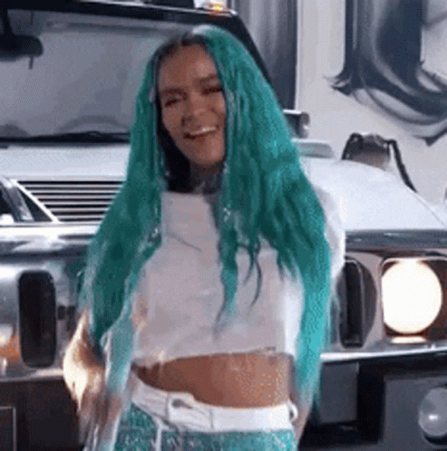 A Woman With Long Green Hair Is Standing In Front Of A White Car . GIF