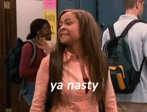 A Woman With Long Hair And A Backpack Is Standing In A Hallway With A Group Of People . GIF