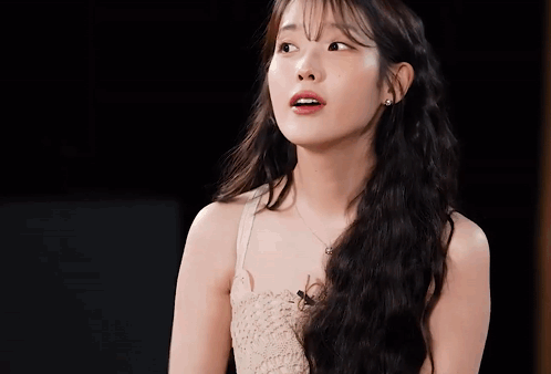 A Woman With Long Hair And A Necklace Looks At The Camera GIF