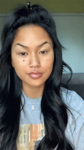 A Woman With Long Hair And A Nose Ring Is Wearing A Grey Shirt GIF