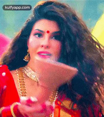 A Woman With Long Hair And A Red Bindi On Her Forehead Is Wearing A Red Dress And Gold Jewelry . GIF