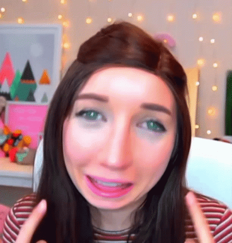 A Woman With Long Hair And Green Eyes Is Making A Funny Face GIF