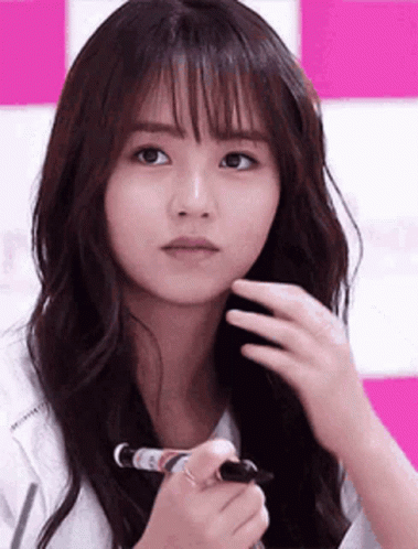 A Woman With Long Hair Is Holding A Marker In Her Hand And Looking At The Camera . GIF