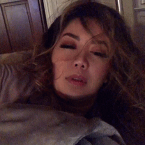 A Woman With Long Hair Is Laying Down With Her Mouth Open GIF