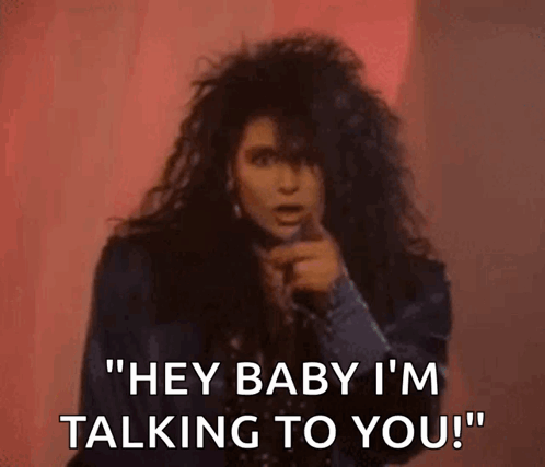 A Woman With Long Hair Is Singing Into A Microphone And Says `` Hey Baby I 'M Talking To You '' . GIF