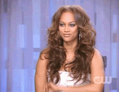 A Woman With Long Hair Is Sitting In A Chair With Her Arms Crossed . GIF