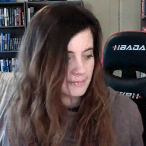A Woman With Long Hair Is Sitting In Front Of A Gaming Chair And Making A Funny Face . GIF