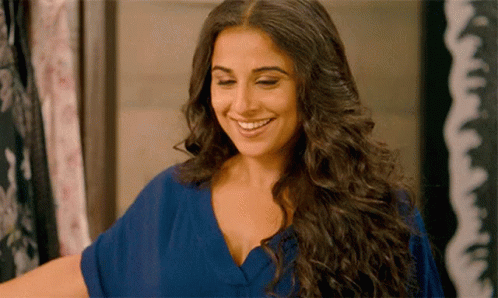 A Woman With Long Hair Is Smiling And Wearing A Blue Dress GIF