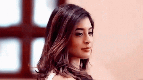 A Woman With Long Hair Is Standing In Front Of A Window Looking At The Camera . GIF