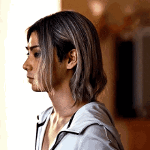A Woman With Long Hair Is Standing In Front Of A Window . GIF