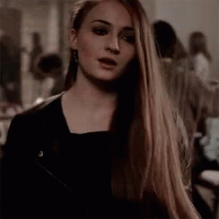 A Woman With Long Hair Is Wearing A Black Jacket And Earrings . GIF