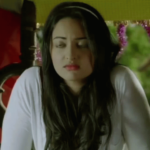 A Woman With Long Hair Is Wearing A Headband And A White Shirt . GIF