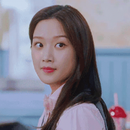 A Woman With Long Hair Is Wearing A Pink Shirt And A Bow Tie And Looking At The Camera . GIF