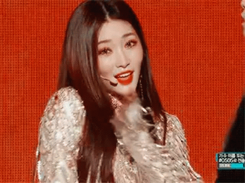 A Woman With Long Hair Is Wearing A Sequined Dress And A Microphone On A Stage . GIF