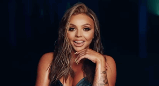 A Woman With Long Nails Is Standing In A Dark Room . GIF