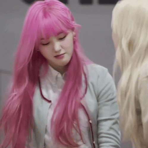 A Woman With Long Pink Hair And Bangs Is Standing Next To Another Woman . GIF