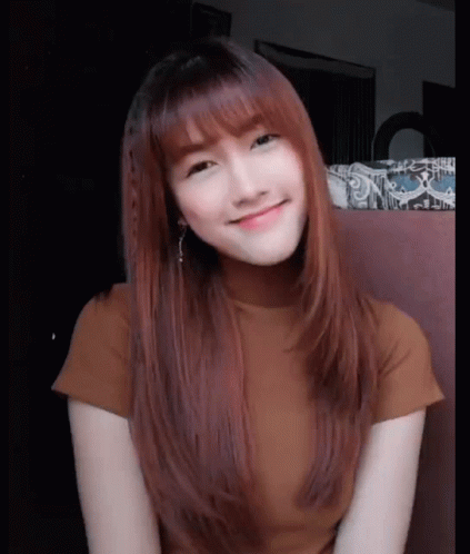 A Woman With Long Red Hair And Bangs Is Smiling For The Camera GIF