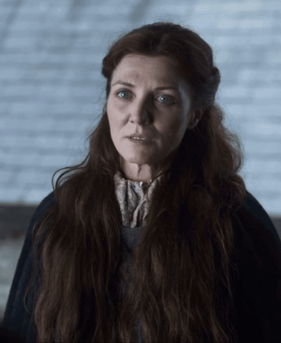 A Woman With Long Red Hair And Blue Eyes Is Wearing A Black Coat GIF