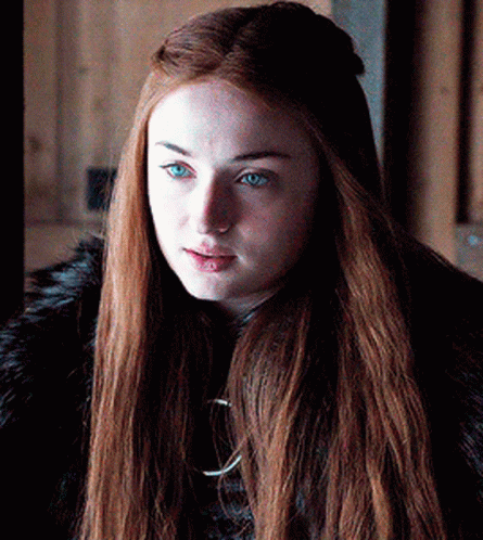 A Woman With Long Red Hair And Blue Eyes Is Wearing A Black Fur Coat . GIF