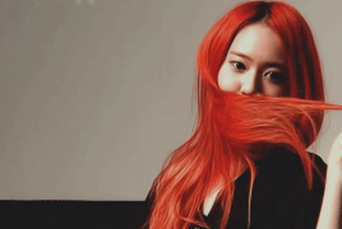 A Woman With Long Red Hair Is Covering Her Face With Her Hair GIF
