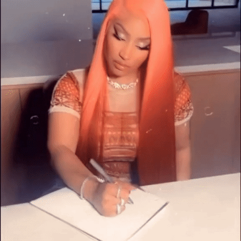 A Woman With Long Red Hair Is Sitting At A Table Writing In A Notebook . GIF