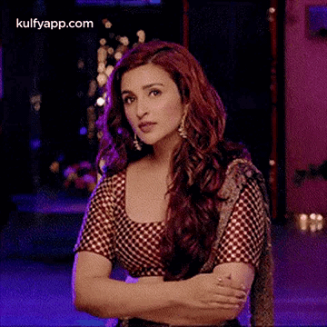 A Woman With Long Red Hair Is Standing With Her Arms Crossed In A Room . GIF