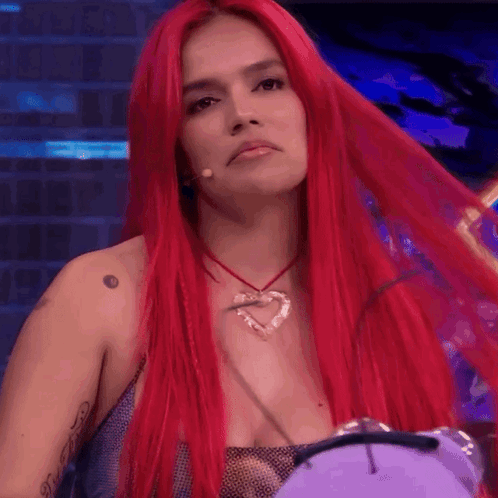 A Woman With Long Red Hair Is Wearing A Heart Necklace GIF