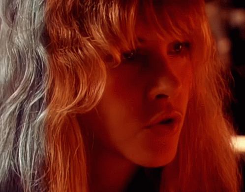 A Woman With Long Red Hair Looks At The Camera GIF
