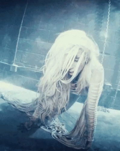 A Woman With Long White Hair Is Laying On The Ground GIF