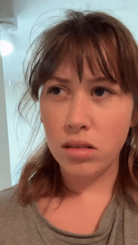 A Woman With Messy Hair Looks At The Camera GIF
