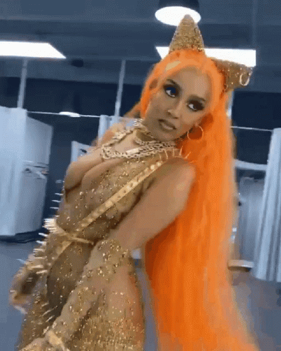 A Woman With Orange Hair Is Wearing A Gold Dress And A Crown GIF