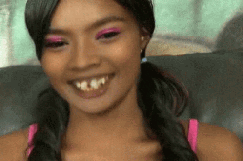 A Woman With Pigtails And Pink Eye Shadow Smiles GIF