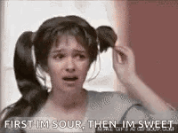A Woman With Pigtails Is Holding Her Hair In A Bun And Says `` First Im Sour Then Im Sweet '' . GIF
