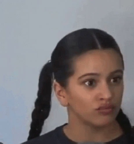 A Woman With Pigtails Is Making A Funny Face And Looking At The Camera . GIF