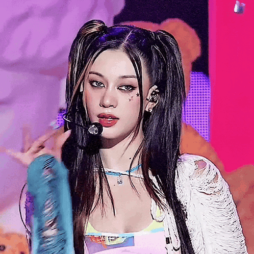 A Woman With Pigtails Is Singing Into A Microphone On A Stage GIF