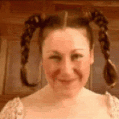 A Woman With Pigtails Is Smiling And Making A Face . GIF
