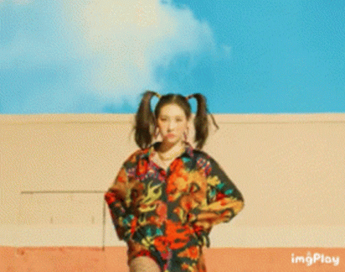 A Woman With Pigtails Is Standing In Front Of A Building With Imgplay Written On The Bottom Right GIF